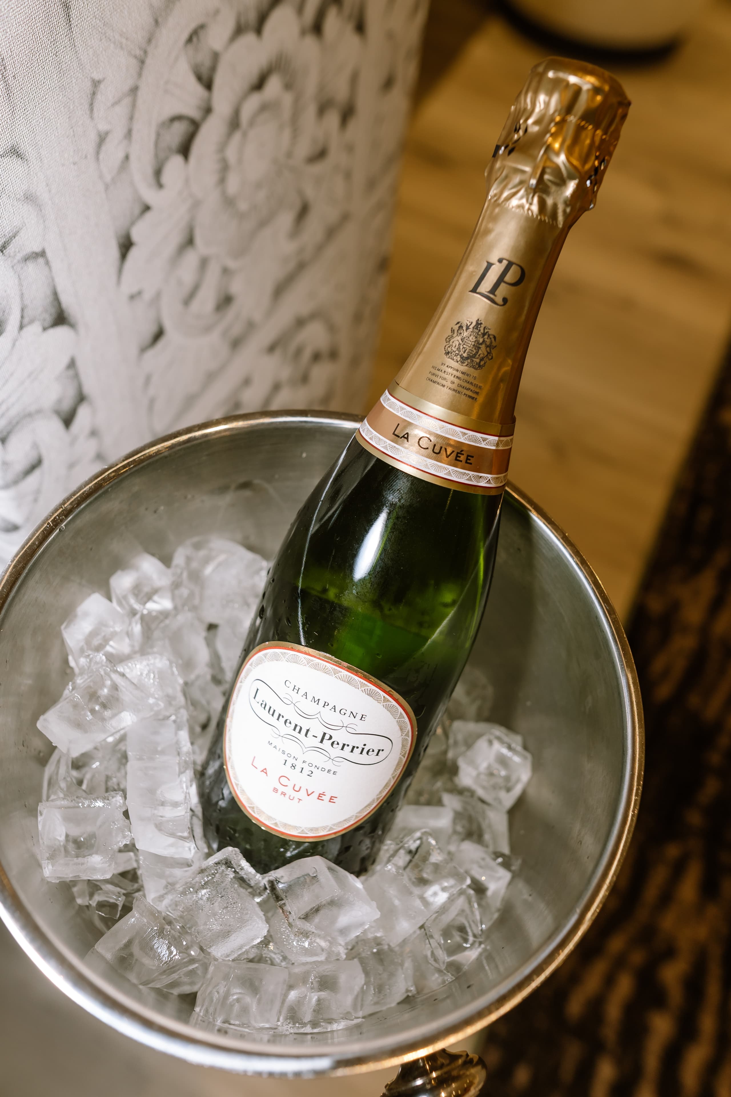 A chilled bottle of Laurent-Perrier La Cuvée champagne rests in a metal bucket of ice