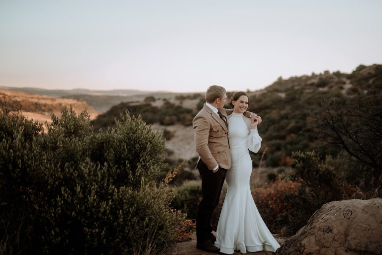 Stylish bride and groom embracing in the mountains